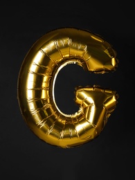 Photo of Golden letter G balloon on black background