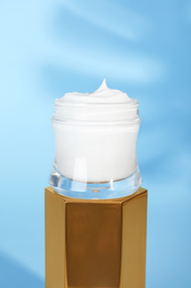 Open jar of cream on display against blue background