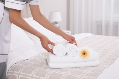 Chambermaid putting flower with fresh towels in hotel room, closeup