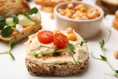 Photo of Delicious sandwich with hummus and ingredients on white table, closeup