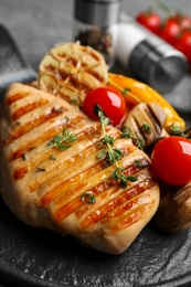 Tasty grilled chicken fillet with tomatoes and thyme on board, closeup