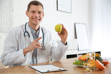 Nutritionist with apple at desk in office