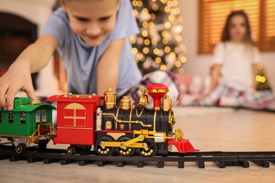 Children playing with colorful toy in room decorated for Christmas, focus on train