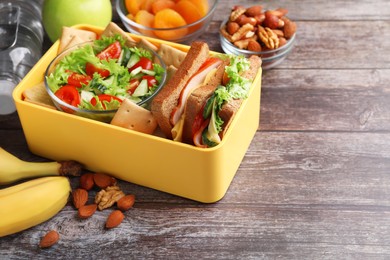 Photo of Lunch box with healthy food on wooden table. Space for text