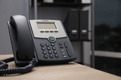 Photo of Stationary phone on wooden desk in office. Hotline service
