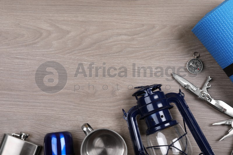 Flat lay composition with different camping equipment on wooden background, space for text