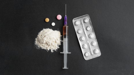 Photo of Powder, syringe and pills on black background, flat lay. Hard drugs