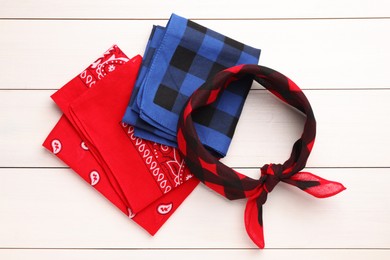 Stylish bandanas with different patterns on white wooden table, flat lay
