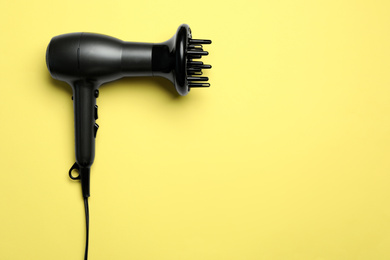 Hair dryer on yellow background, top view with space for text. Professional hairdresser tool