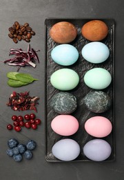 Photo of Naturally painted Easter eggs on black table, flat lay. Coffee beans, red cabbage, spinach, hibiscus, cranberries and blueberries used for coloring