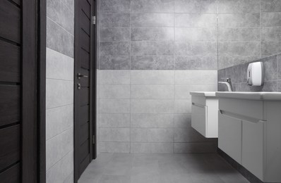 Public toilet interior with stylish white sinks, doors and tiles