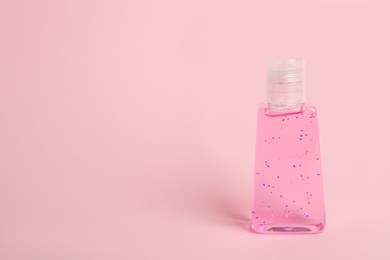Photo of Bottle with antiseptic gel on pink background. Space for text