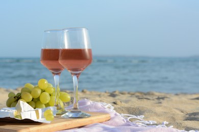 Glasses with rose wine and snacks on sandy seashore. Space for text