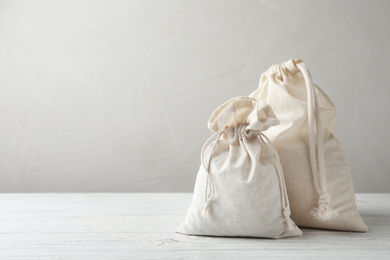 Photo of Full cotton eco bags on white wooden table. Space for text