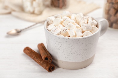 Cup of chocolate milk with marshmallows on wooden table, closeup