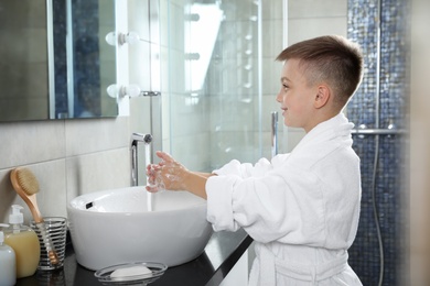 Little boy washing hands with soap in bathroom