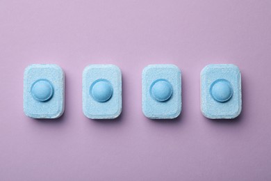 Photo of Water softener tablets on violet background, flat lay