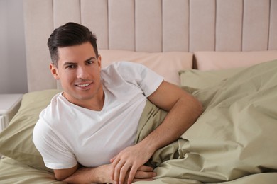 Man lying in comfortable bed with green linens