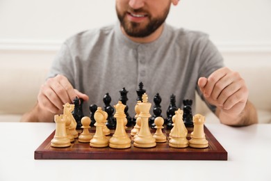 Man playing chess at white table indoors, closeup