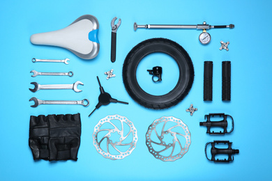 Set of different bicycle tools and parts on light blue background, flat lay