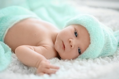 Adorable newborn baby in warm hat lying on bed