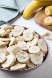 Freeze dried and fresh bananas on white wooden table, closeup