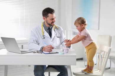 Photo of Pediatrician playing with cute baby in clinic