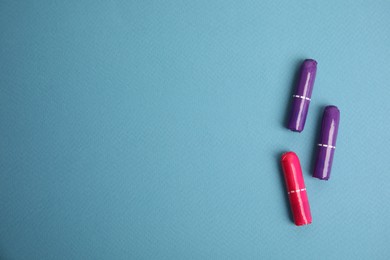 Colorful tampons on blue background, flat lay. Space for text