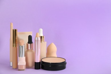 Foundation makeup products on violet background, space for text. Decorative cosmetics