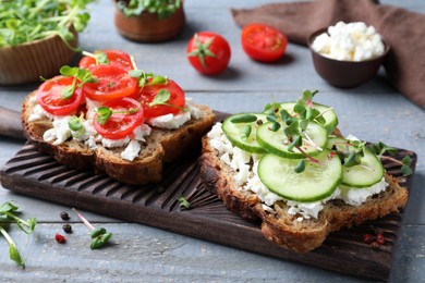 Delicious sandwiches with vegetables, cheese and microgreens on grey wooden table