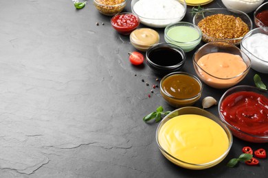 Many different sauces on black table, space for text