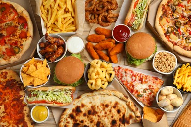 Photo of French fries, pizza and other fast food on wooden table, flat lay