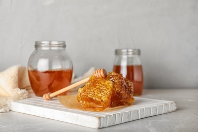 Composition with tasty honey and combs on gray table