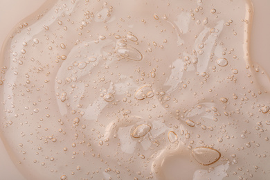 Pure transparent cosmetic gel on beige background, closeup