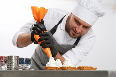 Pastry chef preparing desserts at table in kitchen