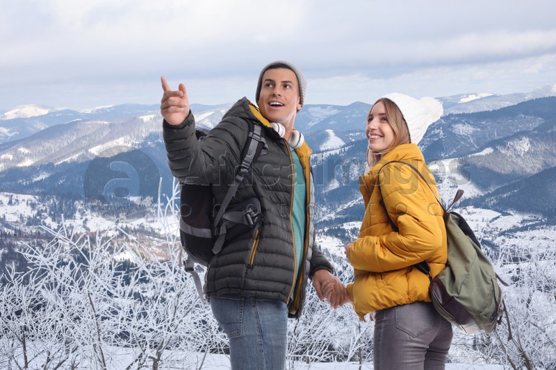 Image of Happy couple with travel backpacks enjoying mountain landscape during vacation trip