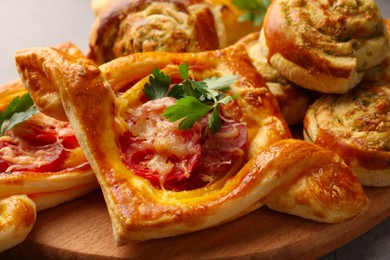Photo of Different delicious puff pastry with tasty filling on wooden board, closeup