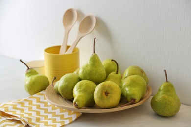 Plate with fresh ripe pears on white table