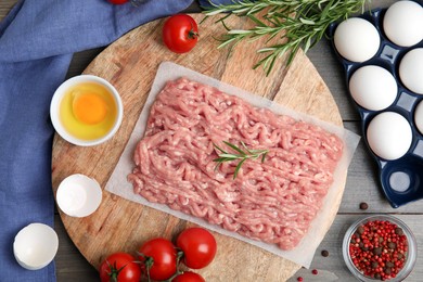 Raw chicken minced meat and ingredients on grey wooden table, flat lay