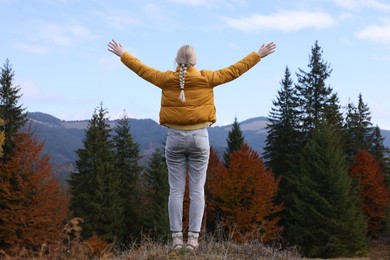 Happy woman in peaceful mountains, back view. Feeling freedom