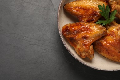 Bowl with delicious fried chicken wings on black table, top view. Space for text