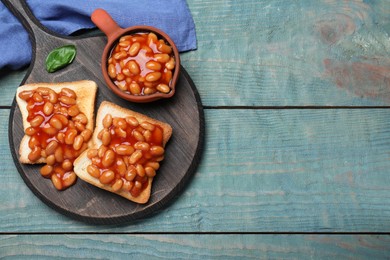 Toasts with delicious canned beans on light blue wooden table, top view. Space for text