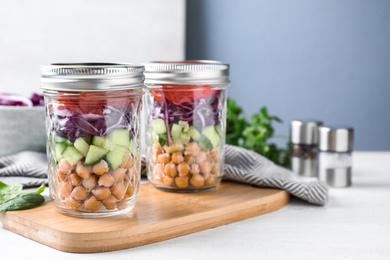 Healthy salad in glass jars on white wooden table. Space for text