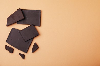 Photo of Broken chocolate bar on brown background, flat lay. Space for text