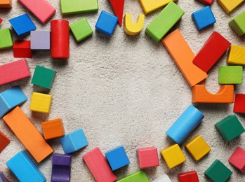 Frame of colorful wooden building blocks on carpet, flat lay. Space for text