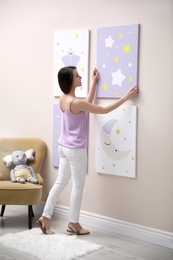 Photo of Decorator hanging picture on pink wall. Children's room interior design