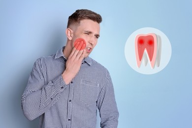 Young man suffering from toothache on light blue background