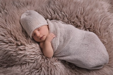 Adorable newborn baby lying on faux fur, top view
