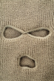 Photo of Beige knitted balaclava as background, closeup view