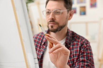 Photo of Man painting on canvas in studio, selective focus. Creative hobby